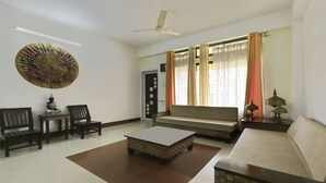 A living room with a sofa, chairs, a coffee table, a fan, and a decorative wall hanging. - Treebo Umal Homestay Ganeshguri (Guwahati)