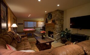 A cozy living room with a stone fireplace, a pool table, and a comfortable seating area.