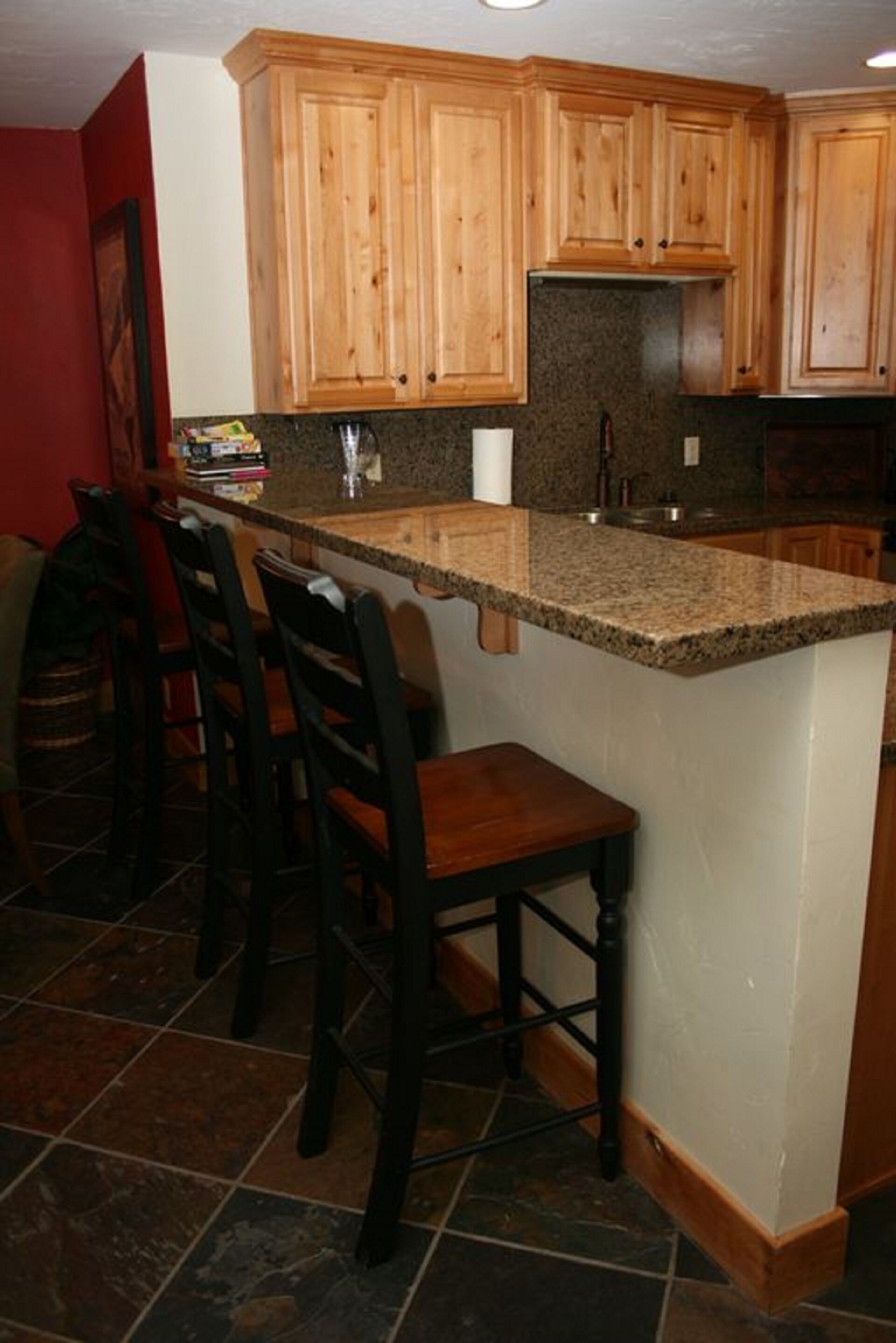 Eine Küche mit Holzausstattung, einer Arbeitsplatte aus Granit und einer Bar.