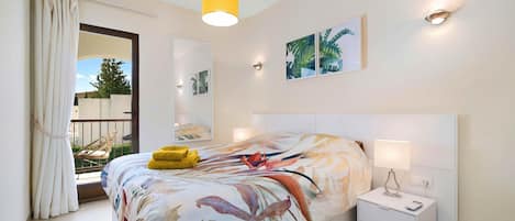 A bedroom with a bed, bedside table, and a window with curtains.