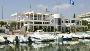 A marina with several boats docked, a modern white building with multiple floors and balconies, and a clear sky. - ASHANTI ZEN GARDEN DELUXE (ALTEA REGION) (La Nucia)
