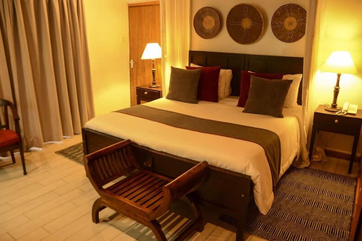 A hotel room with a large bed, two bedside tables with lamps, a wooden chair, and a patterned rug.