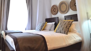 A double bed with a dark headboard, white bedding, and decorative pillows. - Villa Machakos Hotel and Conferencing (Machakos)