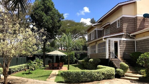 A two-story house with a well-maintained garden, a patio with outdoor furniture, and a staircase leading to the entrance. - Villa Machakos Hotel and Conferencing (Machakos)