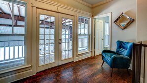 A hallway with wooden flooring, a blue chair, and a door leading to a balcony.