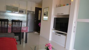 A modern kitchen with white cabinets, a refrigerator, microwave, and a dining area with a table and chairs.