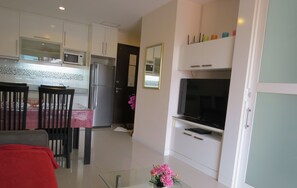 A modern kitchen with white cabinets, a refrigerator, microwave, and a dining area with a table and chairs.