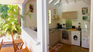 Une cuisine compacte équipée d’un lave-linge, d’un four à micro-ondes et de meubles de rangement en bois.