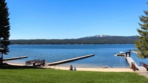 A lakeside view with a dock, a small boat, and a cabin.
