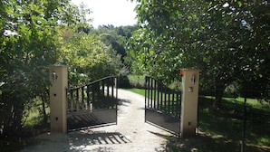 Ein verschlossenes Tor mit einem Kiesweg, der durch ein bewaldetes Gebiet führt.