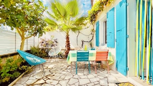 Un patio con piso de piedra, una mesa con sillas y una puerta azul.