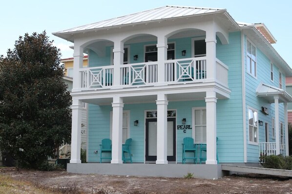 A two-story building with a balcony, a door labeled "PEARL C", and two chairs outside. - THE PEARL at the Emerald Coast 1 Duplex (Santa Rosa Beach)