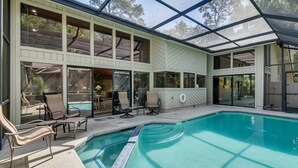 Een modern huis met een ruime glazen patio en een zwembad.