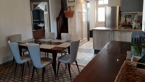 A modern kitchen with a central island, a dining area with a wooden table and chairs, and a staircase leading to an upper level.