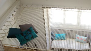 A room with a bed covered by a white net, pillows, and a window.