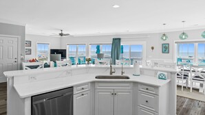 Una cocina moderna con armarios blancos, lavavajillas integrado y una isla grande con pileta.