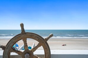 A wooden ship's wheel with a beach and ocean in the background. - 6 bed/6 baths, elevator, Oceanfront, private pool, linens & towels included!!! (Ocean Isle Beach)