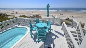 Una terraza con piscina y sillas que da a una playa.