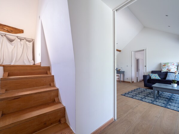Una sala de estar moderna con una escalera, un conjunto de sofás y un comedor.