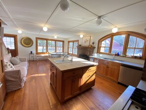A spacious kitchen with wooden cabinets, a large island with a sink, and a stone fireplace.