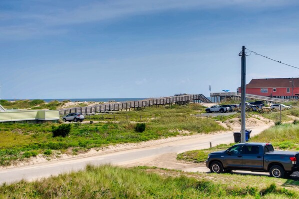 A coastal road with a wooden bridge, a dirt path, and a parked truck.