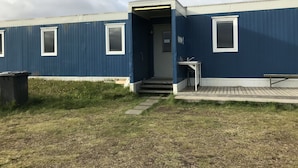 Een blauw gebouw met een deur, een tafeltje en een bankje ervoor.