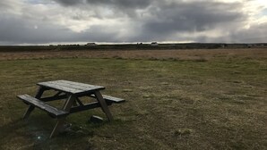 Een picknicktafel in een grasveld onder een bewolkte lucht.
