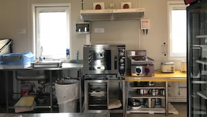 Een professionele keuken met roestvrijstalen apparatuur, een spoelbak en een Coca-Cola koelkast.