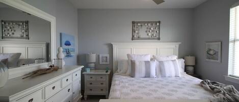 A bedroom with a bed, dresser, nightstands, and a ceiling fan.