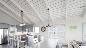 Een moderne keuken met een centraal eiland, witte kasten en roestvrijstalen apparatuur.