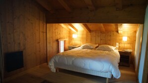 A cozy wooden cabin bedroom with a large bed, two bedside tables, and a nightstand. - Superb chalet in Megève, 5CH, 4 bathrooms, close to center and ski lifts (Megève)