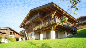 A traditional wooden chalet with a balcony, set on a grassy hillside. - Superb chalet in Megève, 5CH, 4 bathrooms, close to center and ski lifts (Megève)