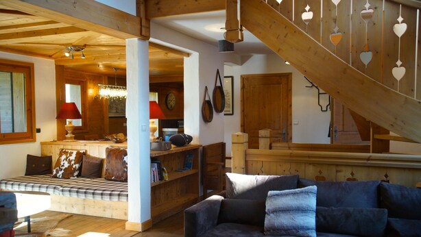 A cozy living room with a sofa, a wooden staircase, and a dining area with a table and chairs. - Superb chalet in Megève, 5CH, 4 bathrooms, close to center and ski lifts (Megève)