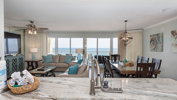 A modern kitchen with a marble countertop, a sink, and a dining area with a view of the ocean. - 3 Bedroom in Long Beach Resort ~ Beautiful with beach chairs included! (Panama City Beach)