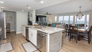 A modern kitchen with a central island, a dining area with a view, and a living space with a ceiling fan. - 3 Bedroom in Long Beach Resort ~ Beautiful with beach chairs included! (Panama City Beach)
