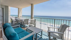A balcony with a view of the beach, furnished with a sofa, chairs, and a table. - 3 Bedroom in Long Beach Resort ~ Beautiful with beach chairs included! (Panama City Beach)