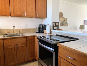 Una cucina moderna con mobili in legno, un lavello in acciaio inox, un forno integrato e una macchina per il caffè.