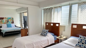 Ett hotellrum med två sängar, en tv, en tavla på väggen och ett fönster med gardiner.