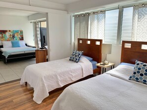 Una camera d'hotel con due letti, una televisione, un quadro al muro e una finestra con tende.