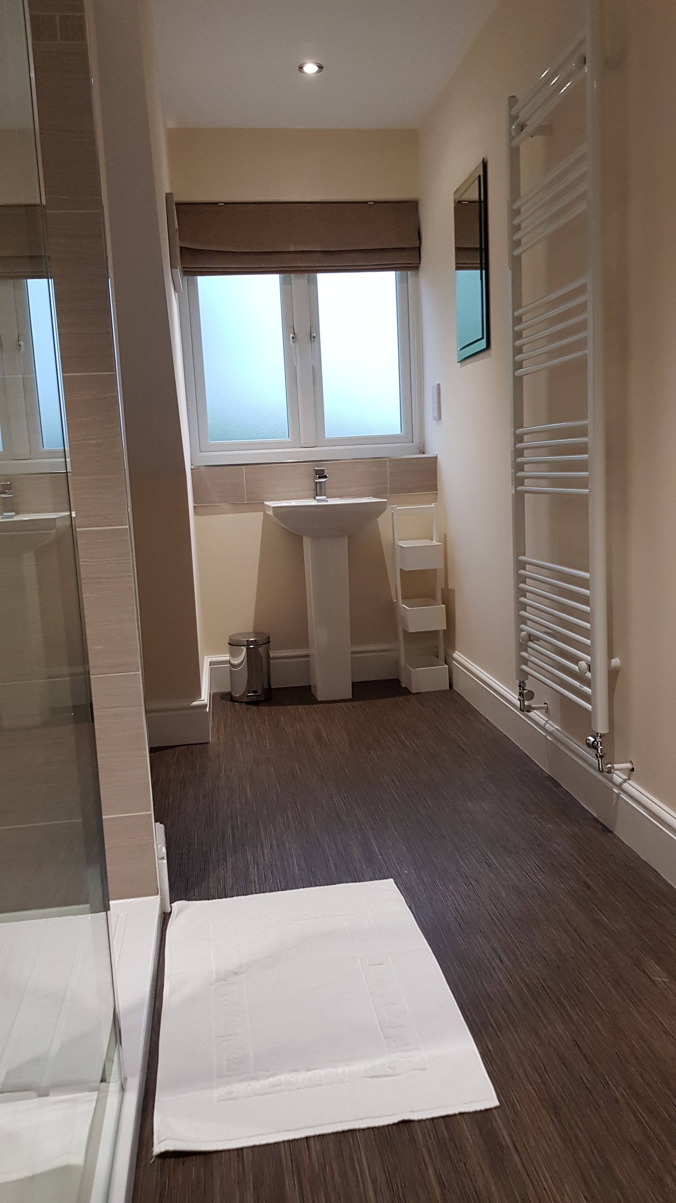 A bathroom with a large window, a sink, and a towel rack.