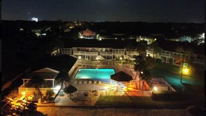 Un resort con piscina, varias edificaciones y una luna visible en el cielo.