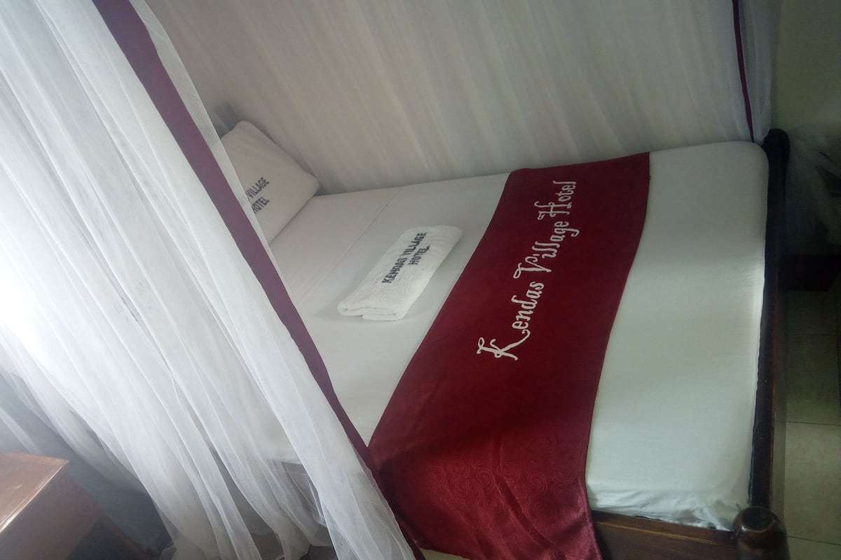 A bed with a white and red bedspread, a white pillow, and a white towel.