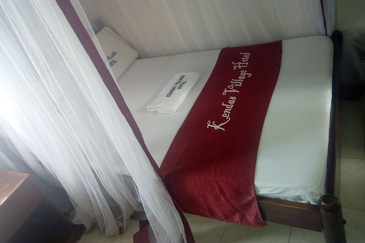 A bed with a white and red bedspread, a white pillow, and a white towel.