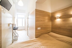 A modern bedroom with a wooden headboard, a bed with a beige quilt, a small stool, and a TV mounted on the wall. - Smart Apartment Kulisha 29a (Lviv)