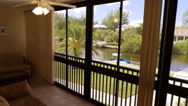 A room with a large window overlooking a water body, a ceiling fan, and a sofa. - The entrance on Siesta Key (Siesta Key)