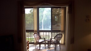 A room with a sliding glass door leading to an outdoor patio with two wicker chairs and a small table. - The entrance on Siesta Key (Siesta Key)