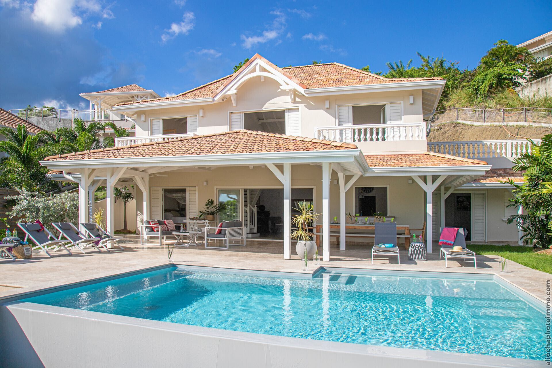 A two-story house with a swimming pool, outdoor seating, and a covered patio area.