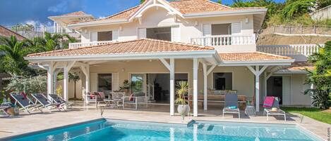 A two-story house with a swimming pool, outdoor seating, and a covered patio area.