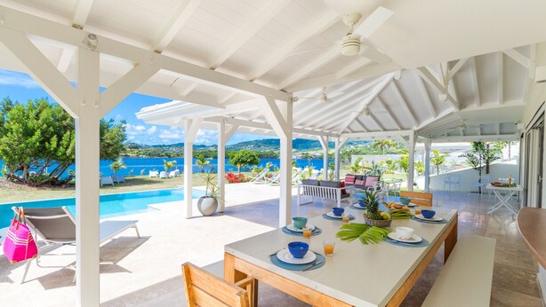 A covered outdoor dining area with a pool and scenic views. - Céladon (Le François)