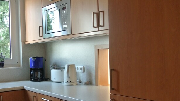 A kitchen with wooden cabinets, a microwave, a coffee maker, and a toaster. - "Nice living in Mainz" Apartment Gisela & Jürgen Will  (Gonsenheim)